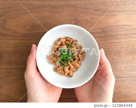 机上で納豆が入った皿を持つ女性の手元 机上で納豆が入った皿を持つ女性の手元 123864348