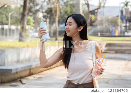 Sustainable lifestyle. Young woman appreciating her reusable cup in a park. Sustainable lifestyle. Young woman appreciating her reusable cup in a park. 123864706