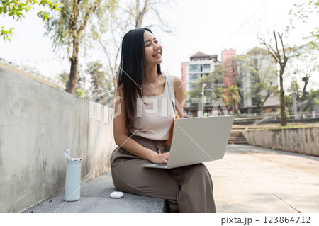 Sustainable lifestyle. Woman working on her laptop outdoors, radiating positivity. 123864712