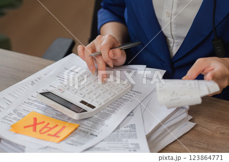 Tax Calculation Process. Individual using a calculator and reviewing tax-related documents for accurate filing. 123864771