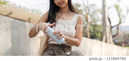 Sustainable lifestyle. Young woman opening her reusable cup while enjoying a peaceful moment outdoors. Sustainable lifestyle. Young woman opening her reusable cup while enjoying a peaceful moment outdoors. 123864780