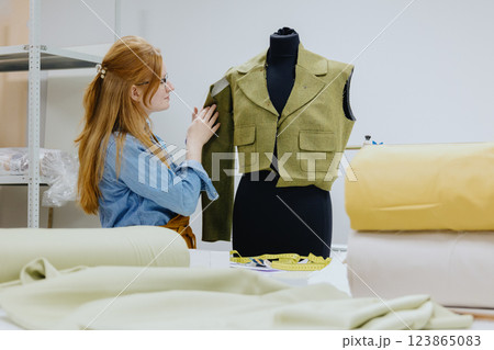 female fashion designer or seamstress tries on a jacket on a mannequin. design patterns 123865083