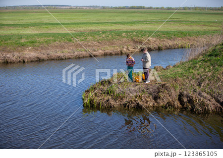 The boys are fishing on a small river. Friends go fishing in the summer. The boys are fishing on a small river. Friends go fishing in the summer. 123865105