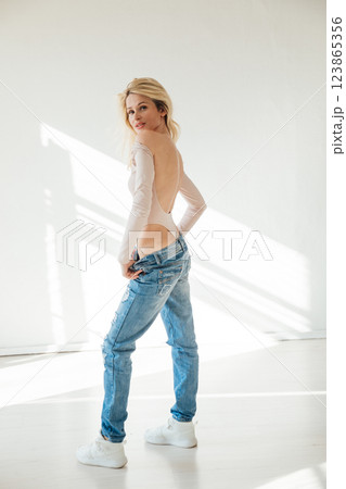 Beautiful fashion blonde woman in jeans by the window Beautiful fashion blonde woman in jeans by the window 123865356