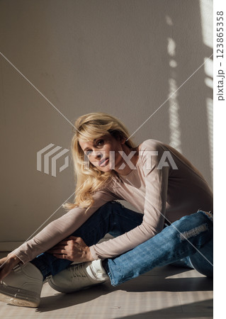 Beautiful fashion blonde woman in jeans by the window Beautiful fashion blonde woman in jeans by the window 123865358