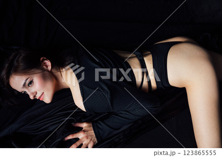 Beautiful slender woman in black lingerie lying on bed 123865555