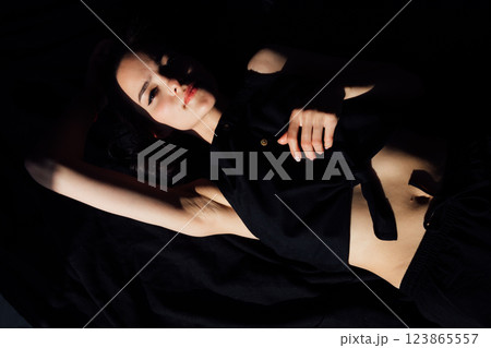 Beautiful slim fashion woman in black lingerie lying on bed 123865557