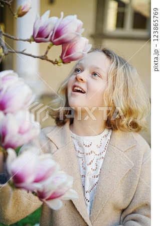 Blonde teenager girl looking at blooming magnolia flower 123865769