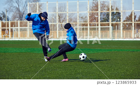 Competitive Play Under Cold Sky. Players challenging each other in fast-paced soccer drill, refining footwork and adaptability on field. Competitive Play Under Cold Sky. Players challenging each other in fast-paced soccer drill, refining footwork and adaptability on field. 123865933