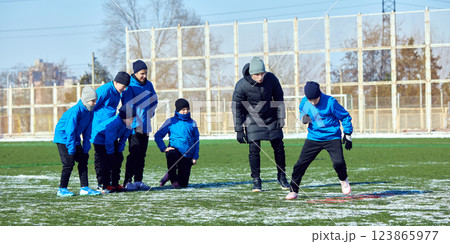 Young football player maneuvering ball through cones with focus, refining footwork during winter training. Pushing Boundaries. 123865977
