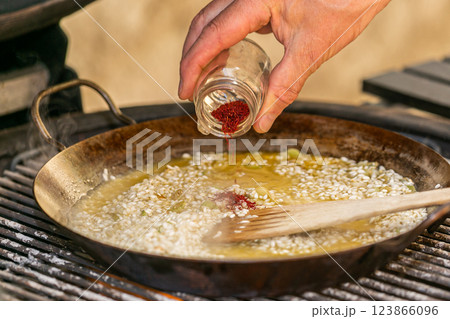 The chef prepares a traditional seafood paella on the grill. Traditional spanish dish. The chef prepares a traditional seafood paella on the grill. Traditional spanish dish. 123866096