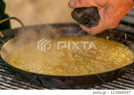The chef prepares a traditional seafood paella on the grill. Traditional spanish dish. 123866097