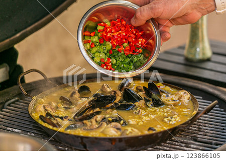 The chef prepares a traditional seafood paella on the grill. Traditional spanish dish. The chef prepares a traditional seafood paella on the grill. Traditional spanish dish. 123866105