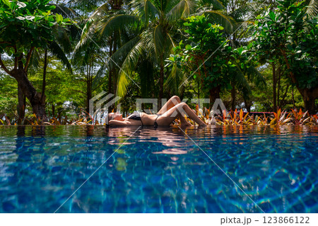Enjoy a delightful experience of relaxing in a tropical pool surrounded by swaying palm trees Enjoy a delightful experience of relaxing in a tropical pool surrounded by swaying palm trees 123866122