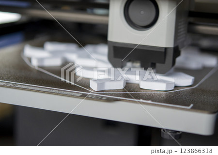 Process of printing on 3D printer. 3D printer creating model from molten plastic close-up. Molten plastic flowing of extruder and forming three-dimensional object white color. Additive technologies 123866318