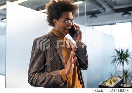 Confident curly-haired young businessman in the office 123866828