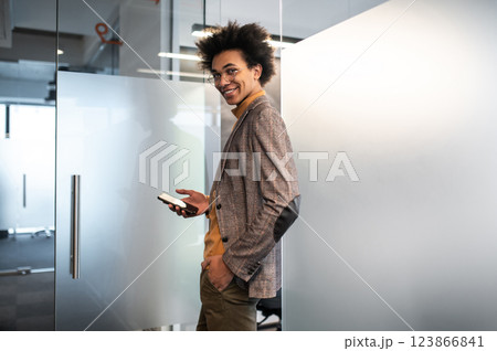 Confident curly-haired young businessman in the office Confident curly-haired young businessman in the office 123866841