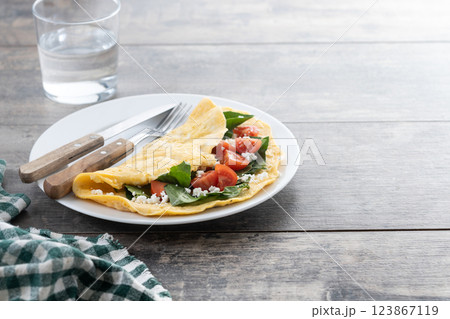 Stuffed omelette with tomatoes and spinach on wooden table Stuffed omelette with tomatoes and spinach on wooden table 123867119