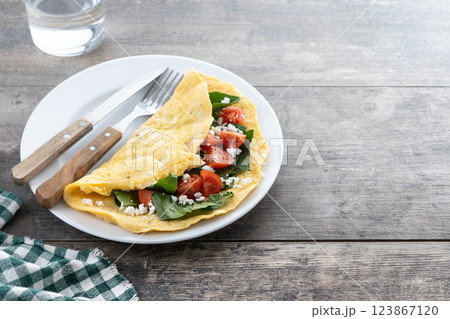 Stuffed omelette with tomatoes and spinach on wooden table Stuffed omelette with tomatoes and spinach on wooden table 123867120