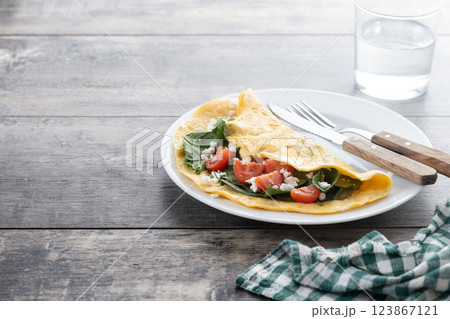 Stuffed omelette with tomatoes and spinach on wooden table Stuffed omelette with tomatoes and spinach on wooden table 123867121
