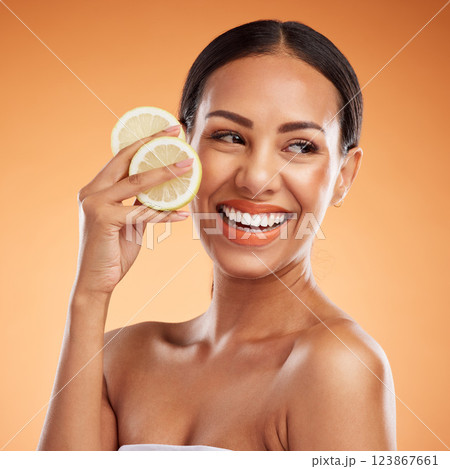 Face, skincare and woman with lemon for health, wellness and vitality on orange studio background. Model, smile and female from Canada with citrus fruit for healthy vitamin c, minerals or nutrition. Face, skincare and woman with lemon for health, wellness and vitality on orange studio background. Model, smile and female from Canada with citrus fruit for healthy vitamin c, minerals or nutrition. 123867661