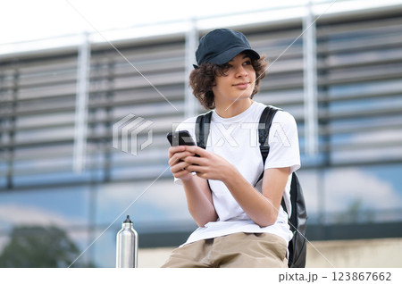 Teenager sitting on the blocks and communicating in the phone Teenager sitting on the blocks and communicating in the phone 123867662