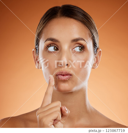 Woman with sugar scrub on lips, skincare with natural product or handmade wellness treatment in studio. Girl thinking on orange background, exfoliate mouth with peeling smooth skin for beauty idea 123867719
