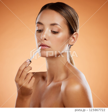 Woman beauty, liquid lipstick and makeup, cosmetics and luxury skincare product on studio background. Aesthetic, beautiful young model headshot applying lip gloss to mouth, shine and grooming glamour 123867722