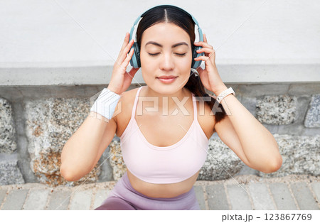 Fitness, music and woman with headphones sitting on ground to relax after outdoor workout, running or yoga. Sports, exercise and streaming motivation or meditation app and enjoying calm playlist. 123867769