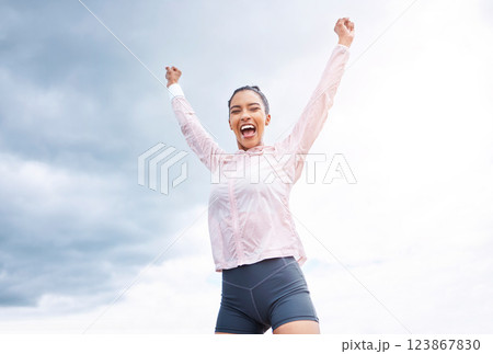 Fitness, woman and runner in victory, win or achievement for sports exercise, workout or training in cloudy sky background. Happy active female runner celebrating, winning and success in the outdoors 123867830