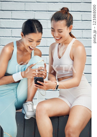Friends, fitness and phone with laughing women on internet sharing funny comic app on social media. Female runner and athlete with smartphone on training, cardio workout and exercise break outdoor 123868000