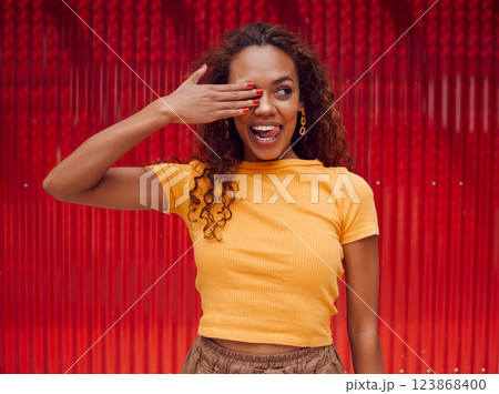 Happy, black woman and tongue out, cover eye or funny face on red background. Fashion, comic and goofy, crazy or silly facial expression of female from South Africa with hand on eyes feeling playful. Happy, black woman and tongue out, cover eye or funny face on red background. Fashion, comic and goofy, crazy or silly facial expression of female from South Africa with hand on eyes feeling playful. 123868400