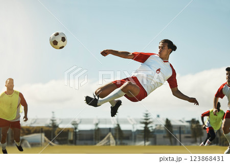 Soccer, game and man kicking a ball during training with the team on a field for sports. Athlete football player in the air to jump for a goal while playing in a professional match or competition 123868431