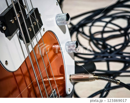 Electric guitar with detailed close-up showing strings, knobs, and tangled cables in a music studio setting 123869017