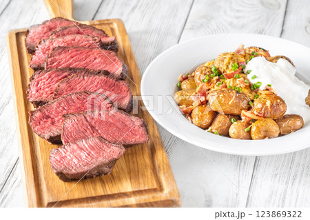 Juicy medium-rare steak with baked potatoes, crispy bacon, and melted cheddar Juicy medium-rare steak with baked potatoes, crispy bacon, and melted cheddar 123869322