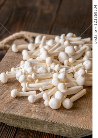 Fresh white beech mushrooms elegantly arranged on a rustic cutting board 123869334