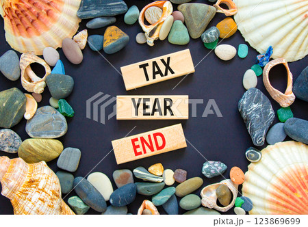 Tax year end symbol. Concept words Tax year end on beautiful wooden blocks. Beautiful black background. Sea shells and sea stones. Business tax year end concept. Copy space. Tax year end symbol. Concept words Tax year end on beautiful wooden blocks. Beautiful black background. Sea shells and sea stones. Business tax year end concept. Copy space. 123869699
