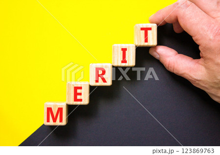 Merit symbol. Concept word Merit on beautiful wooden blocks. Beautiful yellow and black background. Businessman hand. Business lifestyle merit concept. Copy space. 123869763