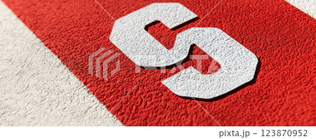 Close up of textured racing bib number on red background, symbolizing competition and athleticism 123870952