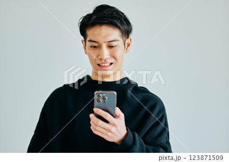 スマホを操作する20代の若い男性 スマホを操作する20代の若い男性 123871509