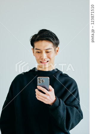 スマホを操作する20代の若い男性 スマホを操作する20代の若い男性 123871510