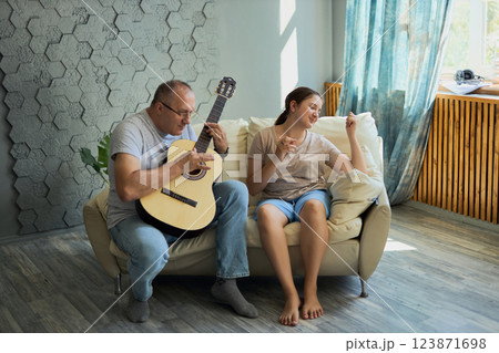 Grandfather and granddaughter sing and play guitar 123871698