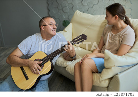 Grandfather and granddaughter sing and play guitar Grandfather and granddaughter sing and play guitar 123871703