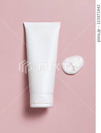 White blank squeeze cosmetic tube near cream smear on light pink top view, mockup White blank squeeze cosmetic tube near cream smear on light pink top view, mockup 123871842