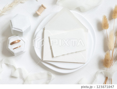 Card on envelope near wedding rings, silk ribbons and hare's tail grass on white top view, mockup Card on envelope near wedding rings, silk ribbons and hare's tail grass on white top view, mockup 123871847