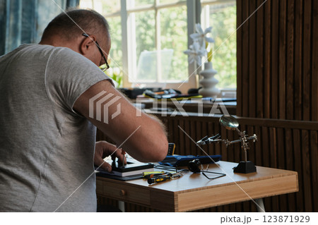 Men wearing denim shirt working with electronic components at his home office Men wearing denim shirt working with electronic components at his home office 123871929