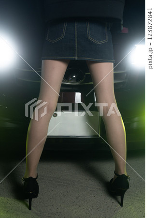 ライトをつけた車の前に立っている女性 ライトをつけた車の前に立っている女性 123872841