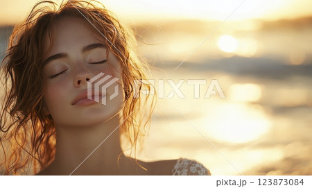 Serene woman with closed eyes at sunset beach relaxation and wellness 123873084