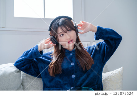 冬のリビングでヘッドホンで音楽を聴く女性 123875524
