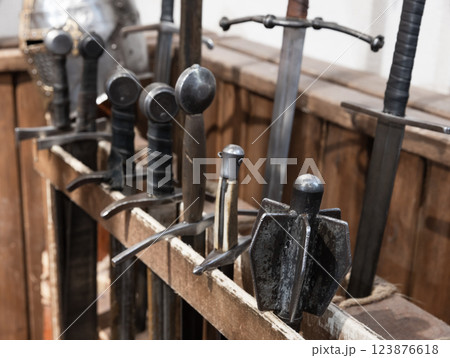 Various medieval swords and weapons are displayed in a wooden rack Various medieval swords and weapons are displayed in a wooden rack 123876618